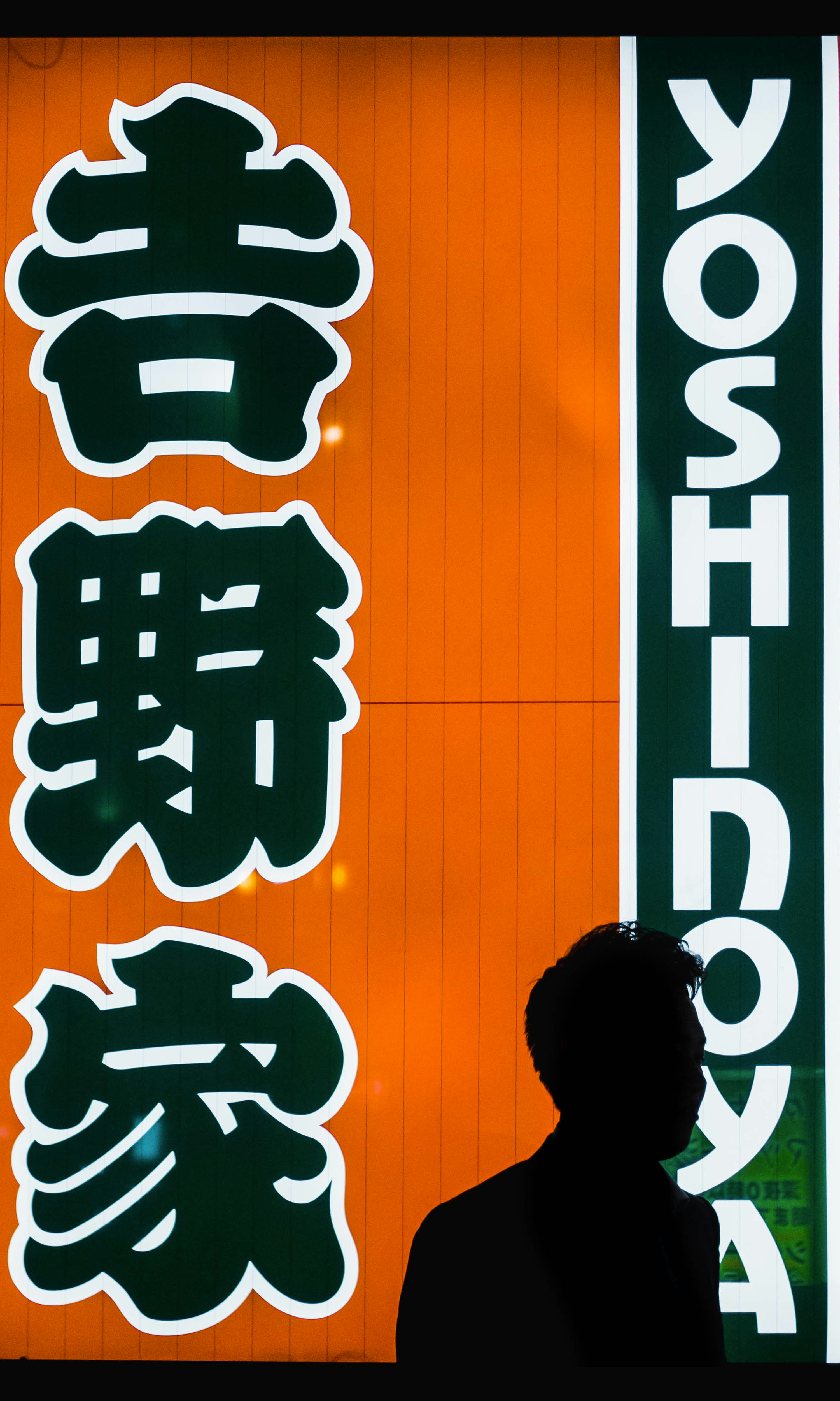 man standing near Yoshinoya store facade